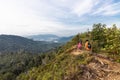 Three person hiking the mountain range overlooking jungle and blue sky