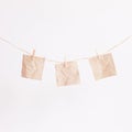 Three pieces of blank square beige sticker paper hanging on the twine rope with little pins on white background isolated Royalty Free Stock Photo