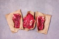 Three Pieces of Raw Fresh Beef Meat Steak on Craft Paper Gray Background Top View Flat Lay Raw Meat Horizontal Royalty Free Stock Photo