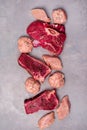 Three Pieces of Raw Fresh Beef Meat Steak Raw Chicken and Raw Chicken Cutlets on Gray Background Vertical Top View Royalty Free Stock Photo