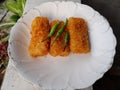 Three pieces of rissoles filled with chicken are served on a white plate.