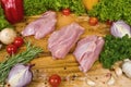 Three pieces of turkey meat on a cutting wooden board with cherry tomatoes, lettuce leaves, garlic, chilli, rosemary Royalty Free Stock Photo