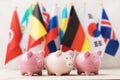 Three piggy banks on the background of flags of different countries, the concept on the theme of the budget