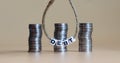 Three pile of coins behind a white cube with the text `DEBT`