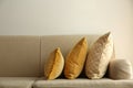 Three pillows on sofa near wall in room.