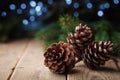 Three pine cones and fir tree branch on rustic wooden table. Christmas greeting card with bokeh. Royalty Free Stock Photo