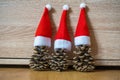 Three pine cones in a red Santa hats like a Christmas tree on wooden background Royalty Free Stock Photo