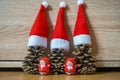 Three pine cones in a red Santa hats like a Christmas tree on wooden background Royalty Free Stock Photo