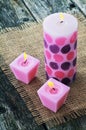 Three pink burning candles on background jute