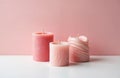 Three pink candles different shapes and textures sit on a white surface against a pastel pink background. Minimalistic, elegant, Royalty Free Stock Photo