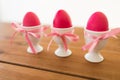 Three pink colored easter eggs in holders on table Royalty Free Stock Photo