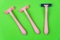 Three pink disposable razors on a green . Personal hygiene items for shaving Royalty Free Stock Photo