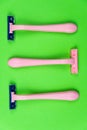 Three pink disposable razors on a green . Personal hygiene items for shaving Royalty Free Stock Photo