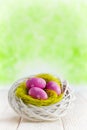 Three Easter eggs in the nest and wooden table on green abstract background Royalty Free Stock Photo