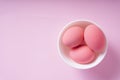 Three pink eggs inside the white bowl over pink background Royalty Free Stock Photo