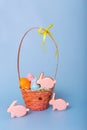 Three pink gingerbread in the form of a rabbit and a basket with decorative Easter eggs