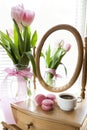 Three pink macaroons and cup of coffee, pink tulips and mirror Royalty Free Stock Photo