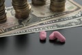 Three pink pills, tablets with dollar bills and stacks of coins Royalty Free Stock Photo