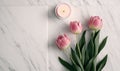 three pink tulips and a candle on a marble surface