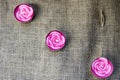 Three pink wax beautiful candles in the form of rose flowers with an unbaked wick on the background of an old brown canvas, harsh,