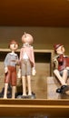 Three Pinocchio puppets in burgundy pink and gray on the shelf