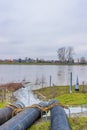 Three pipes of a water pump with water flowing into the Meuse river Royalty Free Stock Photo