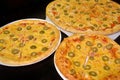 Three pizzas with cheese and olives of different sizes on a dark background Royalty Free Stock Photo