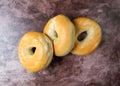 Three plain bagels on a red mottled countertop top view