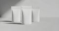 Three plain white packaging pouches stand in soft light with subtle shadows ready for branding Royalty Free Stock Photo