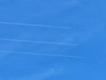 Three planes side by side with exhaust contrails against blue sky