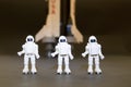 Three plastic astronauts with a saturn V rocket in the blurred background. Concept