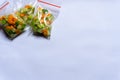 Three plastic bags of pickles made from cucumber and carrot on a white background