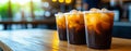 Three plastic cups of cold coffee with ice cubes on wooden table, creating refreshing atmosphere in cozy cafe setting Royalty Free Stock Photo