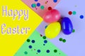 Three plastic easter eggs in blue, green, yellow and pink, with confetti on a geometric mutli-colored background