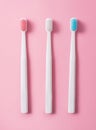 Three plastic toothbrushes on a pink background in pastel colors. Flat lay, top view Royalty Free Stock Photo