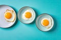 Three Plates of Fried Eggs on a Blue Countertop Top Down View