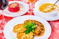 Three plates with lunch dishes on table. Salad with beets, vegetable soup and zucchini fritters