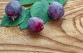 plums, ripe, purple, with green leaves, lie on a wooden board, table, surface Royalty Free Stock Photo