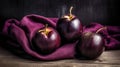 three plums on a purple cloth on a wooden table top with a cloth in the background and a wooden table top with a purple cloth