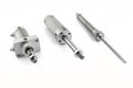 Three pneumatic air cylinders with thread and nut at the end, visible screw-in air dampers, isolated on a white background.