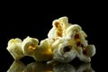 three popcorn isolated on black background with reflection