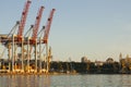 Three port cranes are not in the background of the city. Evening port landscape. Royalty Free Stock Photo