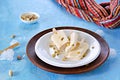 Three portions of the Indian kulfi ice cream with cardamom and pistachios on a white plate on a blue background concrete.