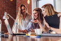 Three positive businesswomen working on laptop discussing joint business project