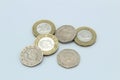 Three pound coins and three twenty pence coins British sterling currency piled on plain background