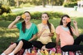 Three pregnant women posing in a picnic park with large colored candies Royalty Free Stock Photo