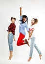 Three pretty african american and caucasian, brunette and blonde teenage girl friends jumping happy smiling on white