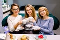 Three pretty Caucasian girl friends spend time together drinking coffee in the cafe, having fun and eating cakes and Royalty Free Stock Photo