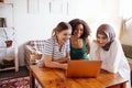 Three pretty female teenagers of different nationalities are looking at the laptop screen and laughing Royalty Free Stock Photo