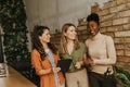 Three young business women with digital tablet standing by the brick wall in the industrial style office Royalty Free Stock Photo
